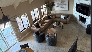 A spacious living room with a large L-shaped sectional sofa, a dining table with four chairs, and a fireplace. - Luxury Riverfront Home in Parker - Private Dock, Mini Pool & Game Room (Parker)