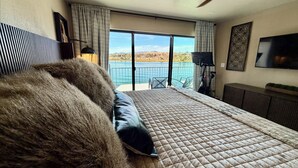 A bedroom with a large bed, a view of a lake, and a motorcycle. - Luxury Riverfront Home in Parker - Private Dock, Mini Pool & Game Room (Parker)