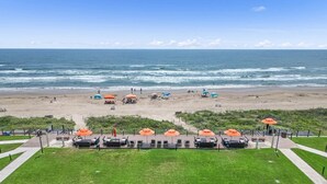 Un hotel sulla spiaggia con zone relax all'aperto, ombrelloni e vista sull'oceano.