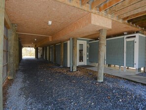 An interior corridor with concrete pillars, a wooden ceiling, and a gravel floor.