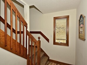 A staircase with wooden railings and carpeted steps leading to a landing.