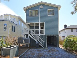 A two-story building with a covered garage and a staircase leading to an upper level.
