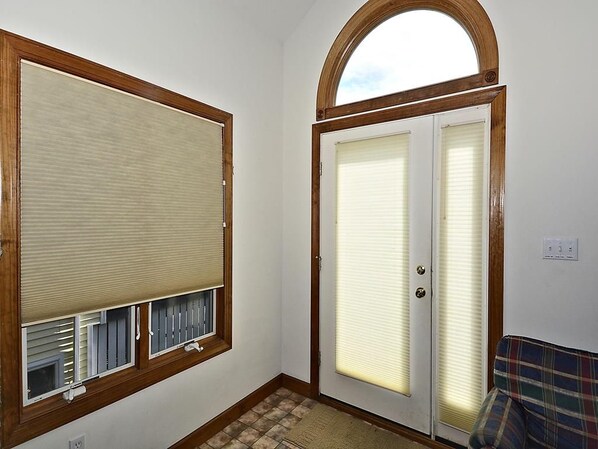 A room with a large window, a door with a window, and a patterned rug.
