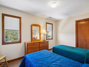 A bedroom with two beds, a dresser, a mirror, and a window.