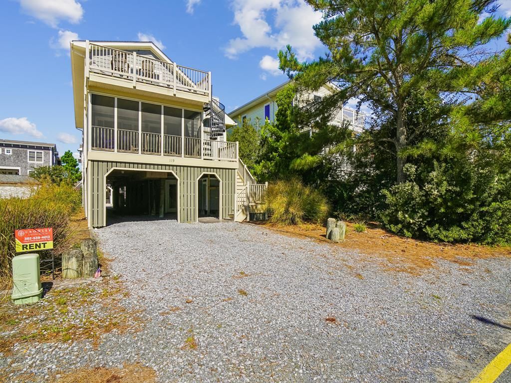 Un bâtiment à deux étages doté d’un balcon, d’une entrée de garage et d’une allée gravillonnée.