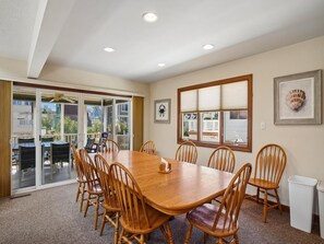 A conference room with a large wooden table and chairs, large windows, and a view of the outdoors.