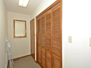 Un couloir avec une armoire en bois, une fenêtre avec des stores et une échelle.