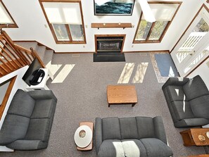 Un salon moderne avec une cheminée, deux canapés, une table basse et un téléviseur.