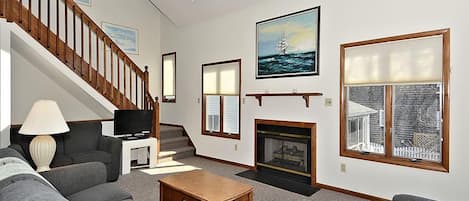 A living room with a fireplace, a television, and a staircase.