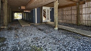 A building with a wooden interior, gravel ground, and a wooden fence.
