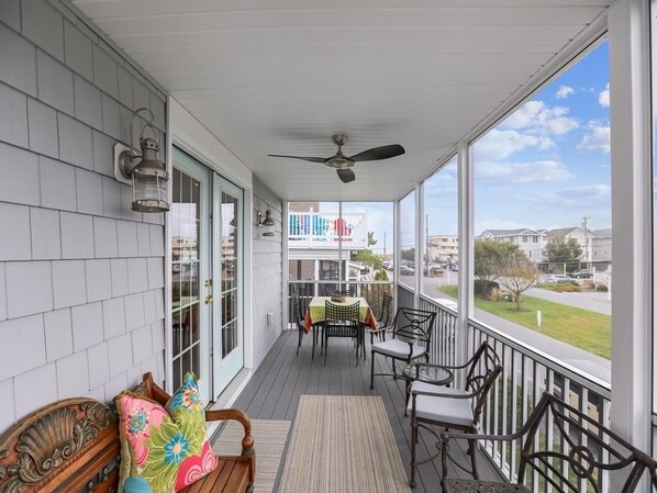 A covered porch with a ceiling fan, a table with chairs, and a view of the neighborhood.