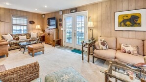 Una sala de estar con sofá, sillón, mesa de centro y televisor.