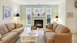 A living room with two sofas, a coffee table, a fireplace, and two lamps.