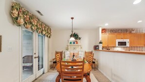 A dining area with a round table and chairs, a kitchen with wooden cabinets, and a sign reading 'BETHANY BEACH'.