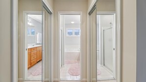 A hallway with glass doors leading to a bathroom and a bedroom.