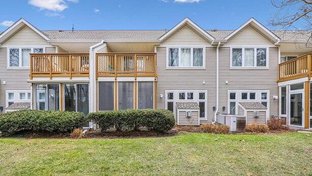 A two-story residential building with a balcony, large windows, and a well-maintained lawn.