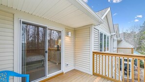 A covered deck with a sliding glass door, a blue plastic chair, and a wooden railing.