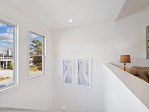 A room with a large window, a white ceiling, and two framed artworks on the wall.