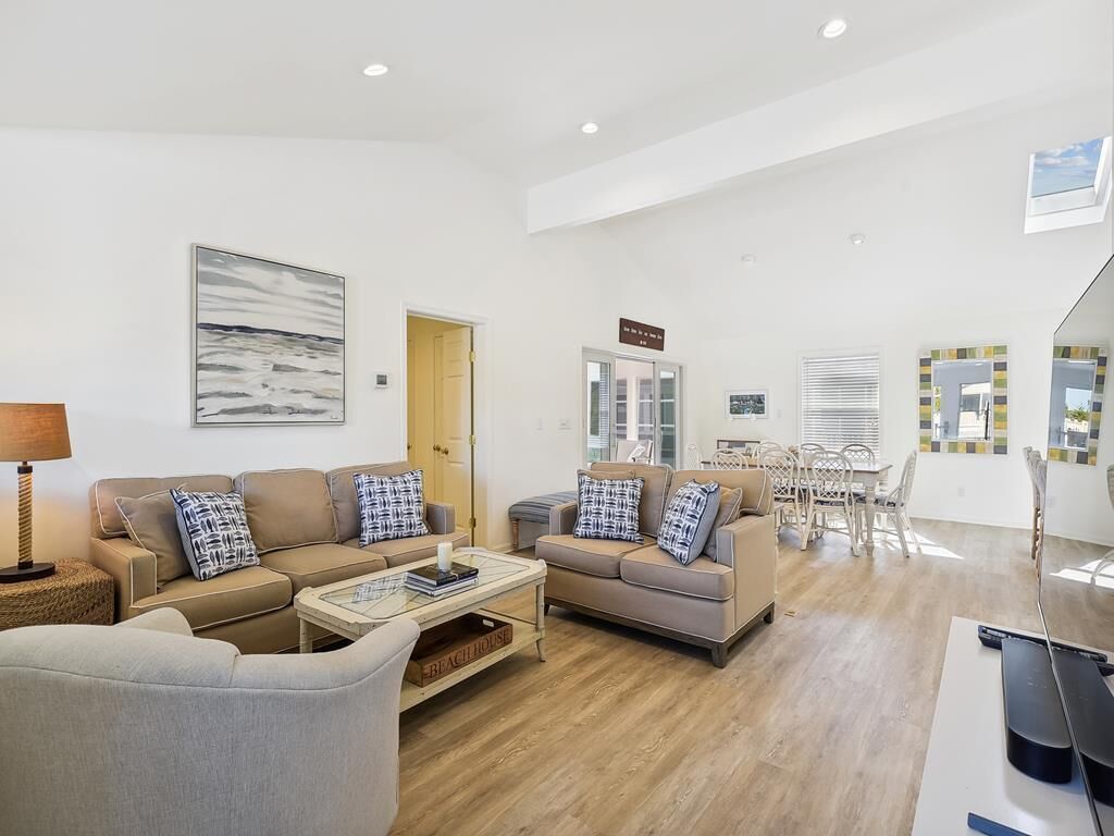 Un vaste espace de vie comprenant deux canapés, une table basse et une table à manger avec des chaises.