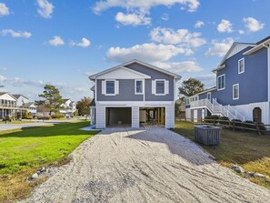 A two-story residential house with a front porch, a driveway, and a well-maintained lawn.