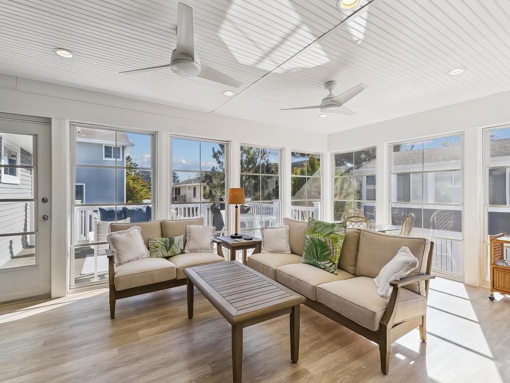 A sunlit room with a sofa, a coffee table, and a ceiling fan.