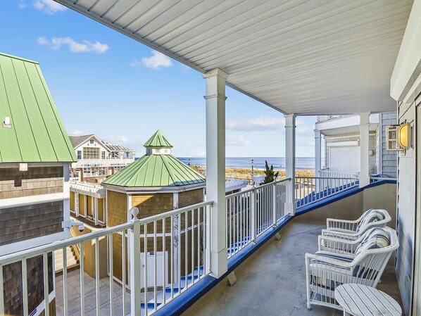 A covered balcony with a view of the beach, white outdoor furniture, and a gazebo. - Oceanfront Condo w/ Pool & Fireplace (Bethany Beach)
