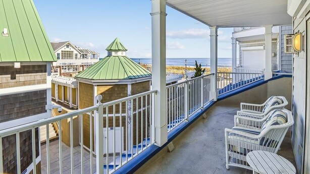 Un balcon abrité avec des balustrades blanches, une vue sur la plage et une structure ressemblant à un belvédère.