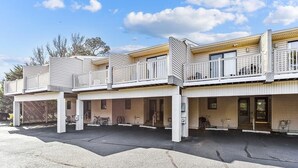 A multi-story building with balconies, a garage, and a parking lot.