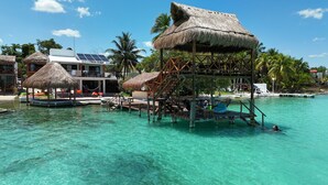 Ein Resort mit Overwater-Bungalows, klarem türkisblauem Wasser und Palmen.