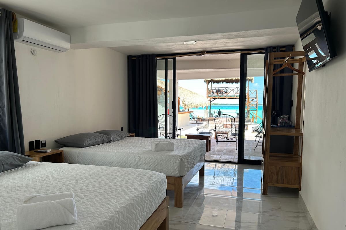 Une chambre d’hôtel avec deux lits, une télévision et un balcon donnant sur la plage.