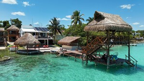 Ein Resort mit überwasser Bungalows, klarem türkisblauem Wasser und einer mit Reet gedeckten Struktur.