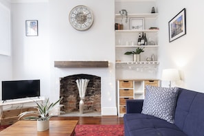 A living room with a fireplace, a TV, a sofa, and a bookshelf.