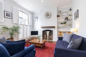 Uma sala de estar com lareira, televisão e mesa de centro.