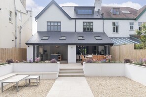 Une maison à deux étages avec un patio couvert et un jardin.