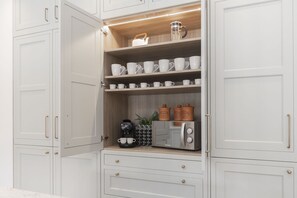 Une cuisine avec des meubles blancs, une machine à café et un grille-pain.