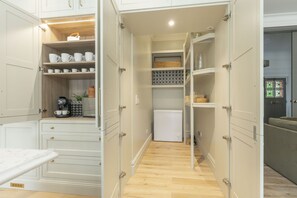 Una cocina compacta con muebles blancos, un refrigerador empotrado y una máquina de café.