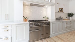 Une cuisine avec des meubles blancs, une cuisinière en acier inoxydable et un dosseret en marbre.