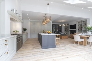 Une cuisine moderne avec des meubles blancs, un îlot central et un coin repas comprenant une table et des chaises en bois.