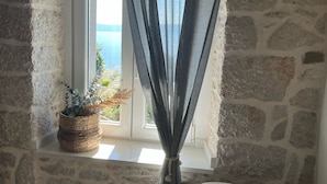 Ein Zimmer mit Steinwänden und einem Fenster mit Blick auf ein Gewässer.