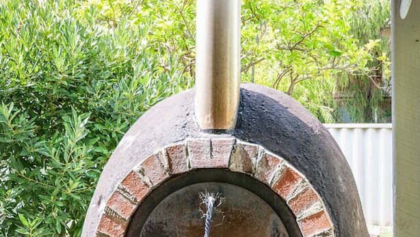 A brick-built outdoor pizza oven with a chimney, surrounded by greenery. - Pebbles by the Bay - Quaint Central Busselton (Busselton)