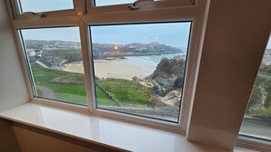 A view from a window overlooking a beach with a distant cityscape.