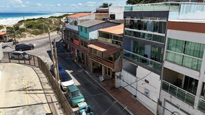 A coastal street with buildings, a road, and a view of the beach.