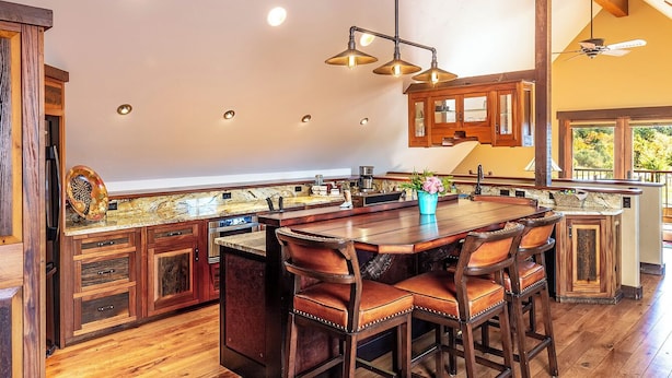 Une cuisine spacieuse dotée d’un grand îlot central, de meubles en bois et d’un coin bar.