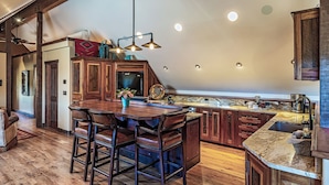 A spacious kitchen with a large island, wooden cabinets, and a bar area with stools.
