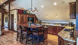 Una cocina amplia con una isla grande, armarios de madera y una zona de bar con taburetes.