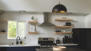 A modern kitchen with a stove, microwave, and black cabinets. - Lakefront Cottage with Sauna- #3 Chinook (Wasilla)