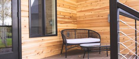 Une cabane en bois avec un banc et une table sur le porche.