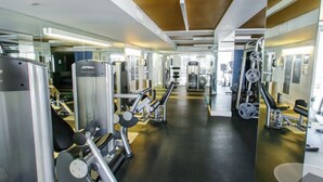 Een moderne sportschool met diverse fitnessapparaten, spiegelwanden en een centrale looproute.