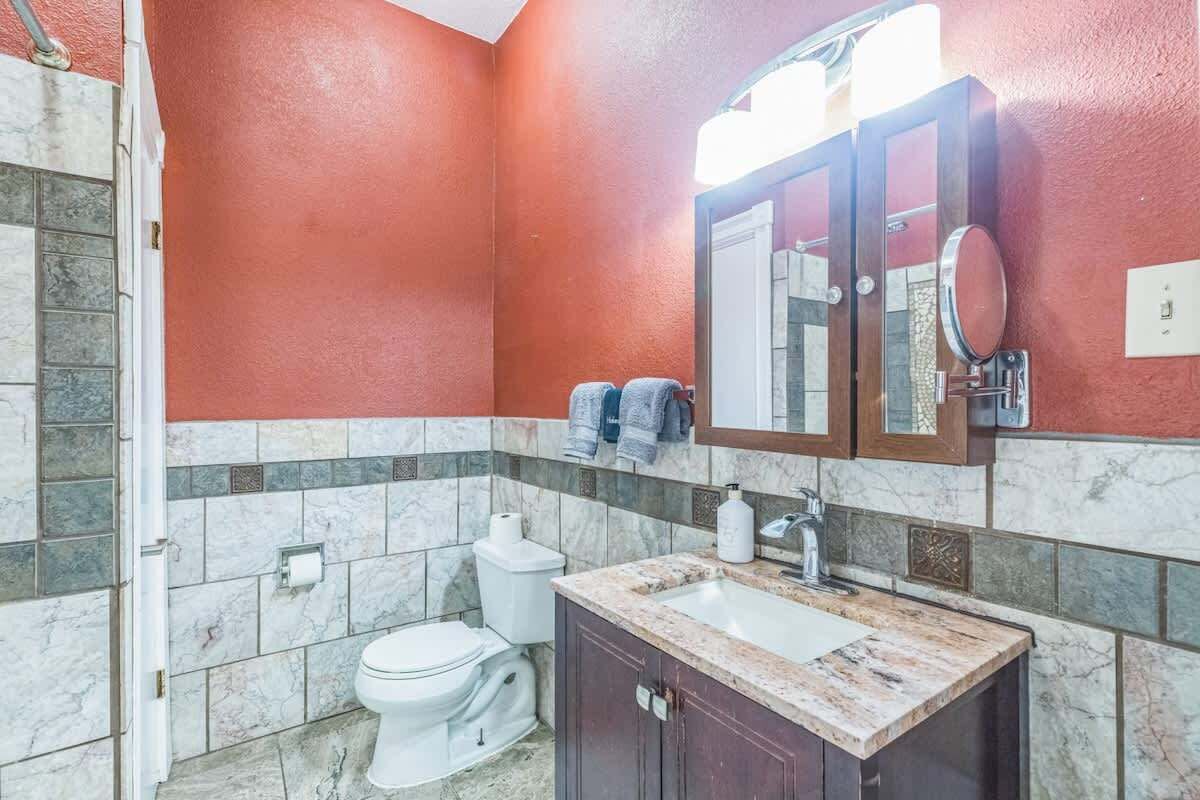A bathroom with a toilet, sink, and mirror.