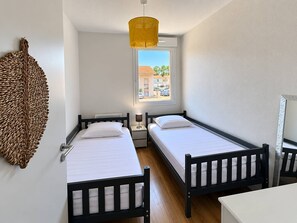 Ein Zimmer mit zwei Betten, einem Fenster mit Blick, einer Hängelampe und einer Wanddekoration.